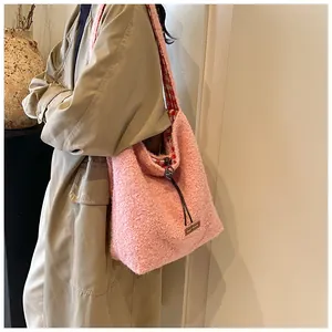 Pink plush tote bag with drawstring closure and red plaid lining in street style view