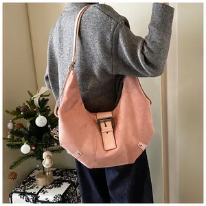 Pink suede crescent bag detail featuring large metal buckle and adjustable shoulder strap