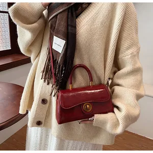 Detail of a vintage dark red leather handbag featuring a golden metal twist-lock clasp