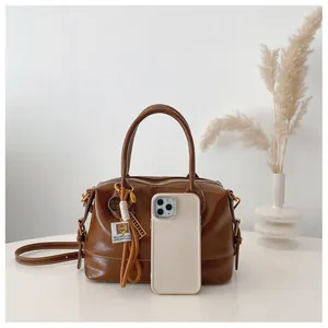 Brown oil wax leather Boston bag detail showing medium size compared to a smartphone