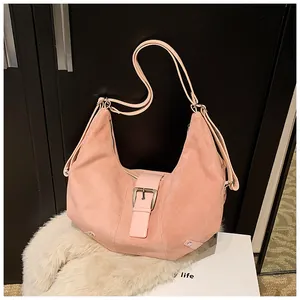 Close-up of pink suede hobo bag with decorative buckle and thin shoulder straps