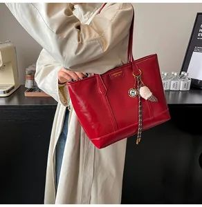 Détails du sac cabas en similicuir rouge avec logo doré et pendentif pompon à carreaux