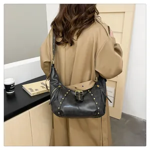 Detail der schwarzen Vintage-Hobo-Tasche mit Goldnieten getragen mit einem Trenchcoat