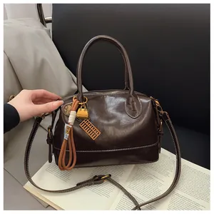 Detailed macro view of dark brown gloss leather Boston bag with tassels and gold charms