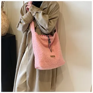 Detail of pink plush tote bag with black drawstring closure and internal plaid lining