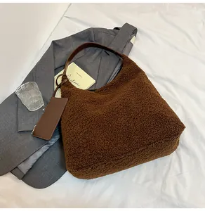 Detail of soft brown faux shearling tote with leather straps on a grey blazer context