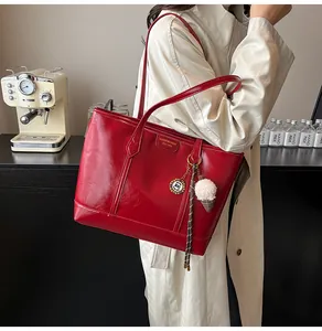 Détail d'un sac cabas rouge en similicuir brillant avec un pendentif glace en peluche