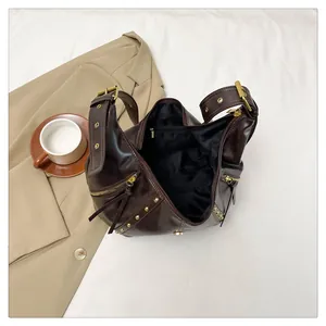 Details einer kaffeebraunen Hobo-Tasche mit Goldnieten und geräumigen Innentaschen