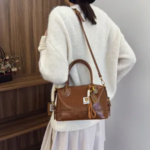 Brown vintage Boston shoulder bag with chic charms shown on model in cozy setting
