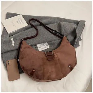 Detailed view of brown suede crescent bag texture on a wool blazer background