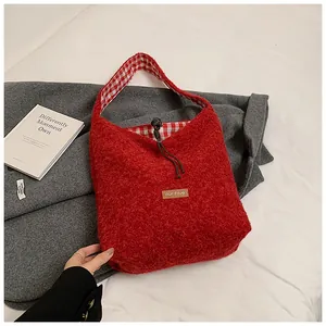 Detail of red plush tote bag showing fuzzy texture, leather tag, and checkered lining
