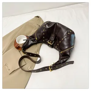 Detail der dunkelbraunen Vintage-Halbmondtasche mit Goldnieten und Metallakzenten
