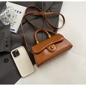 Close-up of brown polished leather mini bag with gold twist lock on grey blazer