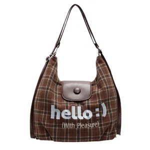 Brown plaid tote bag with leather trim and hello embroidery in a clean studio setting