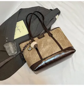 Détail du sac cabas en toile beige avec bordures en cuir verni marron et breloque gland