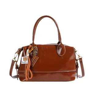 Glossy brown retro boston handbag with adjustable strap and decorative charms