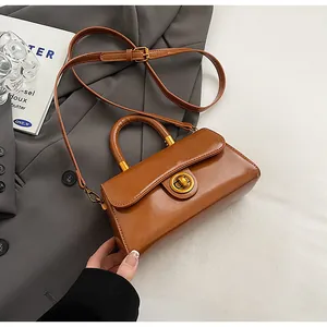 Detail view of brown leather handbag featuring a vintage gold twist lock and top handle
