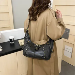 Schwarze Vintage-Hobo-Tasche mit goldenen Nieten und Schnallen-Detail am Modell