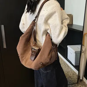 Brown suede hobo shoulder bag with metal buckle strap shown from a side-rear angle