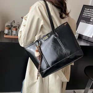 Sac fourre-tout noir brillant en similicuir PU avec charme en peluche et logo doré chic