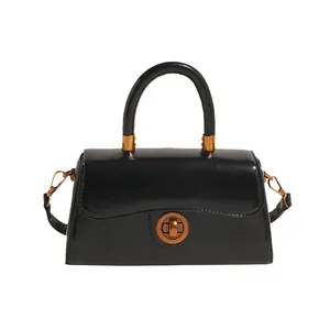 Retro black leather top-handle crossbody bag with vintage gold hardware on white background