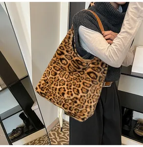 Detail of plush leopard print tote bag with brown leather shoulder straps worn by model