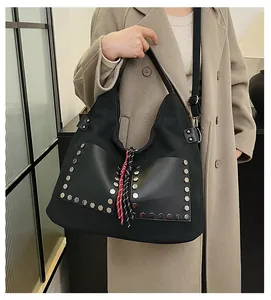 Detail of black canvas tote bag with leather panels and silver hexagonal rivets