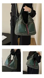 Detail of green suede tote bag featuring silver studs and colorful woven tassel charm