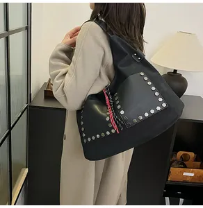 Detail of black tote bag with silver rivets and colorful woven strap on a beige coat