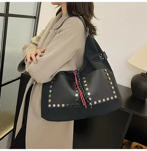 Side view of large black hobo tote bag with silver studs and braided rope detail