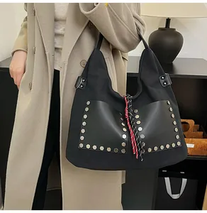 Detail of large black tote bag with silver studs and red-black braided tassel