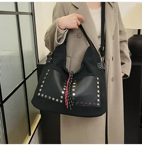 Detail of canvas tote bag with silver hexagonal rivets and red-black woven tassel