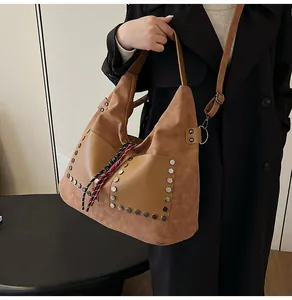 Close-up of a large brown bucket bag with rivet detailing and woven drawstring accents