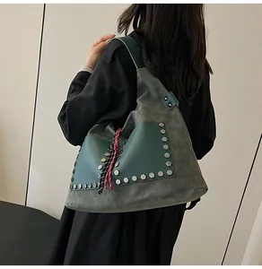 Detail of grey-green bucket bag with studded pockets and colorful woven rope charm