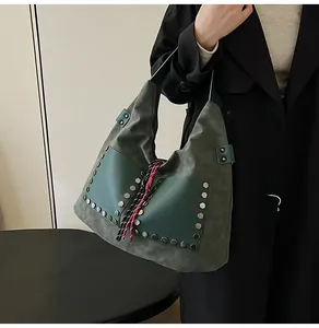 Detail of dark olive green bucket bag with silver hexagonal rivets and woven tassel