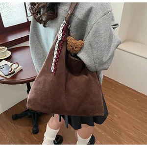 Detail of dark brown suede tote bag with plush bear charm and decorative silk scarf