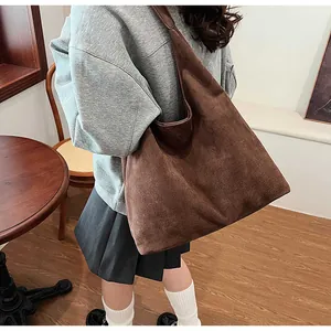 Detail of a large brown suede tote bag worn on shoulder for minimalist office commute