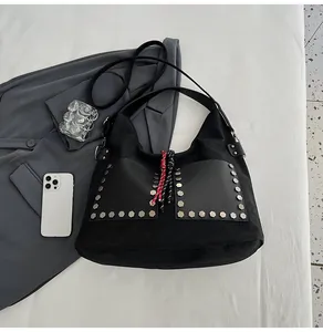 Detailed view of black hobo bag featuring hexagonal metal studs and woven rope accents