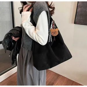 Close-up of black canvas tote bag with a cute brown plush bear charm detail