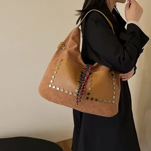 Retro caramel brown bucket bag in matte finish with metal rivets and woven rope pendant