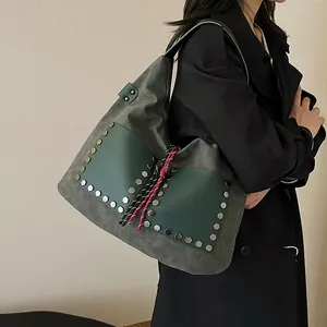 Large dark green bucket bag with silver hexagonal rivets and woven tassel details