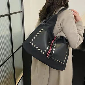 Large black nylon and leather bucket bag with silver hexagonal rivets on a female model