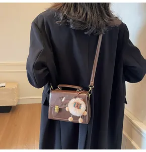 Detail view of brown retro PU leather crossbody bag with cute dog embossing and plush pendant
