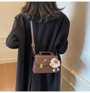 Close-up of brown vintage leather crossbody bag with cute dog embroidery and plush charm