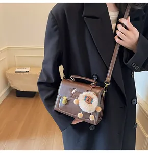 Detail of vintage brown crossbody bag with dachshund embroidery and lion charm