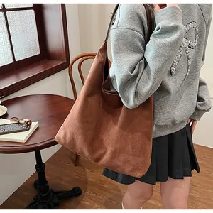 Macro detail of the dark brown suede tote bag with minimalist shoulder strap