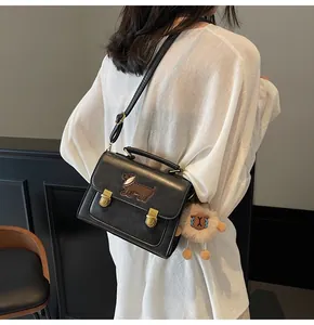 Detail of black crossbody bag with dachshund embroidery and plush sheep charm on model