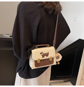 Close-up of retro color-block crossbody bag with dachshund embroidery and lion plush charm