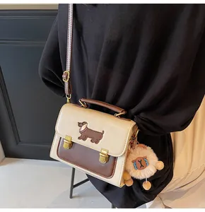 Detail of minimalist cream square handbag with dachshund embroidery and lion plush charm