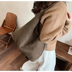 Detail of a large dark brown suede tote bag with seamless shoulder strap for office